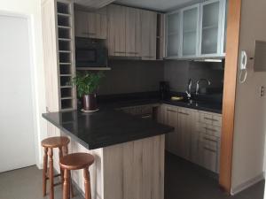 uma cozinha com armários de madeira e um balcão preto em Excelente Departamento en Reñaca em Viña del Mar