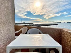 ein Tisch und Stühle auf einem Balkon mit Blick auf das Wasser in der Unterkunft Voile de Mer 2 - Les Pieds dans l'eau, CLIM, Wifi, 3 personnes in Fos-sur-Mer