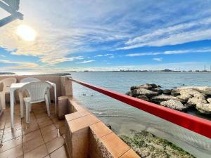 einen Balkon mit einem Tisch und Stühlen auf dem Wasser in der Unterkunft Voile de Mer 2 - Les Pieds dans l'eau, CLIM, Wifi, 3 personnes in Fos-sur-Mer