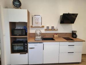 a kitchen with white cabinets and a sink and a microwave at Studio centre d Arcis in Arcis-sur-Aube