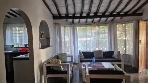 a living room with a couch and some windows at Boma Banda Diani - Pepu Cottage in Diani Beach