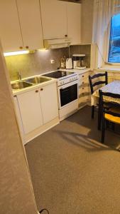 a kitchen with white cabinets and a sink and a table at Donsö Lägenhet in Gothenburg