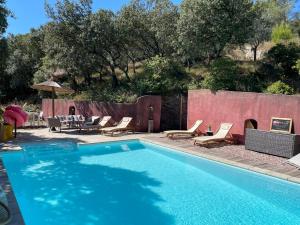 een zwembad met ligstoelen en een tafel bij Jolie annexe du mas dans le cœur de la garrigue nîmoise in Nîmes