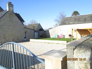 a house with a fence and chairs in the yard at maison des trois rivières in Trévières