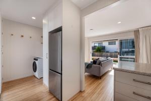 a kitchen with a refrigerator and a living room at Mount Central Hideaway in Mount Maunganui +20 photos