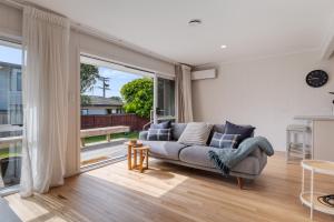 a living room with a couch and a large window at Mount Central Hideaway in Mount Maunganui