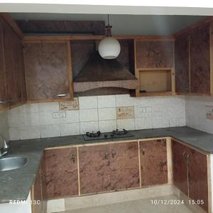 a kitchen with wooden cabinets and a sink and a light at 5 Marla safari valley bahria Phase 8 in Rawalpindi