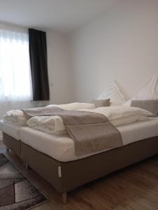 ein Bett mit weißen Laken und Kissen in einem Schlafzimmer in der Unterkunft Appartment Messe in Köln