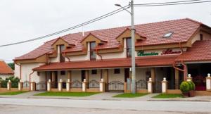 a building with a red roof on a street at Penzión Altana in Ludanice