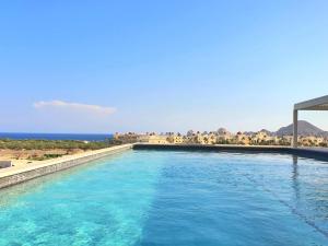 a swimming pool with the ocean in the background at Amaterra 304D Seaside Luxe Condo in Cabo San Lucas