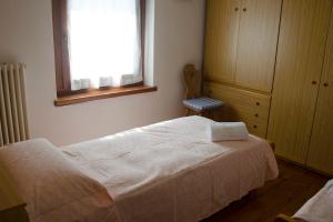 a bedroom with a white bed and a window at Casa Vacanze Tel 121 in Pieve Tesino