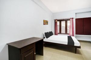 a bedroom with a bed and a desk and a window at Super Hotel O THE HOME SPOT in Trivandrum