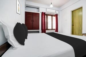 a bedroom with a white bed and red curtains at Super Hotel O THE HOME SPOT in Trivandrum +23 photos