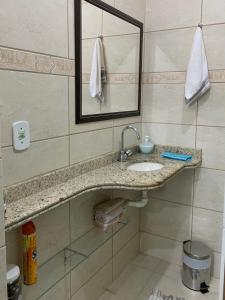a bathroom with a sink and a mirror at Suites Arraial do Cabo in Arraial do Cabo
