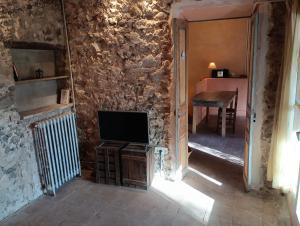 Habitación con pared de piedra, TV y mesa. en Ca la iaia Veva, en Sant Joan les Fonts