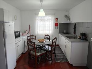 a kitchen with a small table and chairs in it at Rosário Guest House in Lajes
