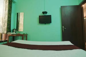 a bedroom with a bed and a tv on the wall at Hotel Shaurya By Sharma 0nline Solution Haridwar in Haridwār