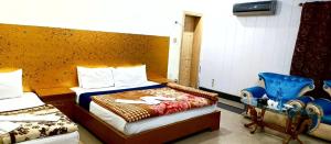 a bedroom with two beds and a blue chair at Hotel Palace Lodge Multan in Multan