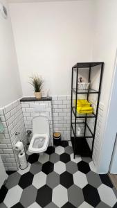 Un baño con inodoro y suelo a cuadros en blanco y negro. en Wodniak, en Ostróda