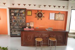 an orange wall with two stools in a room at Hotel Sunrise Kovalam in Kovalam +19 photos