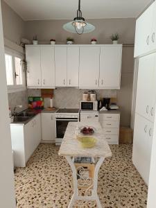 a kitchen with white cabinets and a table in it at Itea's Garden House in Kírra
