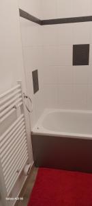 baño con bañera blanca y alfombra roja en joli appartement bord de mer, en Pornic 5 fotos más