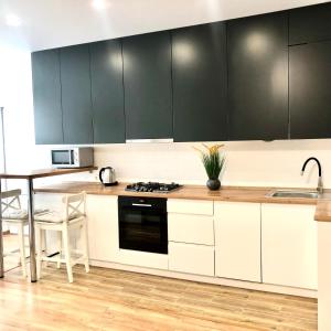 a kitchen with white and black cabinets and a table at OSapart Apartment in a complex Semycvit in Lviv