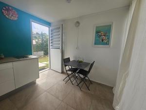 a kitchen with a table and chairs in a room at Appartement Bleu Corail avec Jacuzzi in Les Trois-Îlets