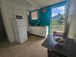 a kitchen with a refrigerator and a table with a bowl of fruit at Appartement Bleu Corail avec Jacuzzi in Les Trois-Îlets