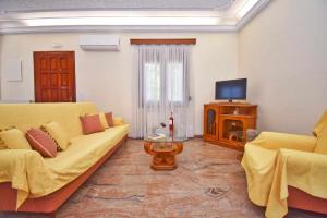 a living room with a yellow couch and a television at KarolinaHouse in Ágios Matthaíos