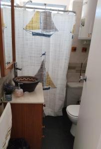 a bathroom with a shower curtain with a sink and a toilet at Edificio céntrico en el Este, Torre Gorlero in Punta del Este