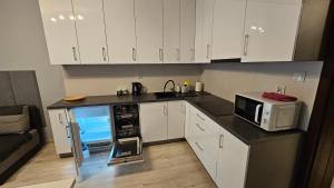 a kitchen with white cabinets and a microwave at Jedenastka in Płock