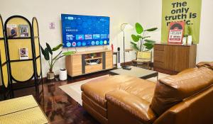 a living room with a brown leather couch and a tv at 3BR 5BedVilla Silom China town BTS Surasak Special offer in Chinatown
