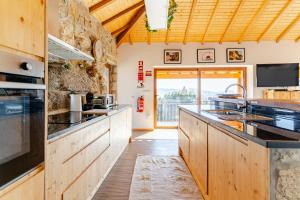 a large kitchen with wooden cabinets and a large window at CASA DO SOL , Turismo Rural in Celorico de Basto