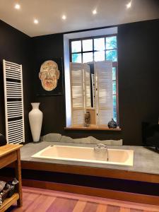 a large bath tub in a room with a window at Le Clos du Châtelain, in Profondeville