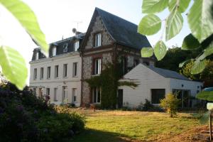 ein großes weißes Haus mit schwarzem Dach in der Unterkunft Les Sous Bois in Saint-Laurent-de-Brévedent