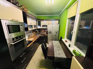 a kitchen with green walls and a table in it at BLA Apartman in Szentes