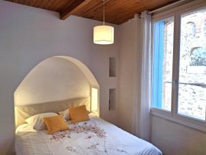 Un dormitorio con una cama blanca con un arco encima. en Appartement T6. Emplacement et vue mer d'exception, en Collioure