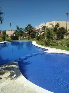 una grande piscina con acqua blu in un resort di Condominio Flamingos a Ixtapa