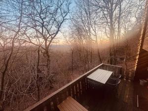 un banco sentado en una terraza de madera con vistas en The Forest Cabin Durbuy, en Durbuy