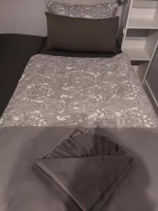 a bed with a gray comforter and a pillow at Sea Lodge Mardorf in Neustadt am Rübenberge