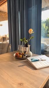 a table with a plate of fruit and a vase with a flower at Sea Lodge Mardorf in Neustadt am Rübenberge