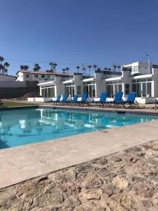a swimming pool with blue chairs and a building at Beachfront Boutique Villa Cazadores in Rosarito