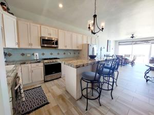 a kitchen with white cabinets and a island with bar stools at Beachfront Boutique Villa Cazadores in Rosarito