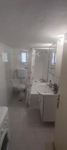 a white bathroom with a sink and a toilet at Άνετο διαμέρισμα στο κέντρο της πόλης in Xanthi