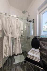 a bathroom with a glass shower stall with white robes at Villa Berfami - Managed by Excelsior Villas in Podstrana +49 photos