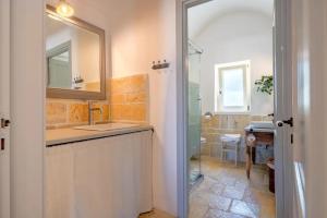 un bagno con lavandino, specchio e doccia di Apulia Trulli Macco Macco Locorotondo a Locorotondo