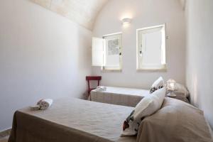 una camera da letto con due letti e due finestre di Apulia Trulli Macco Macco Locorotondo a Locorotondo