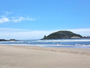 a sandy beach with an island in the ocean at Casa de Praia 3 Dormitórios Imbituba Santa Catarina in Imbituba