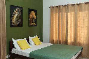 a bedroom with a bed with yellow and green at Orange valley Residency Thodupuzha in Thodupuzha